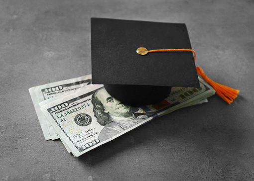 diploma and graduation hat with rolled up money