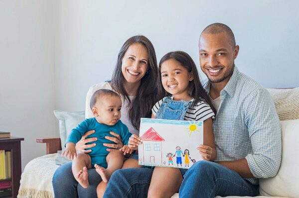 family with daughter holding drawing of house