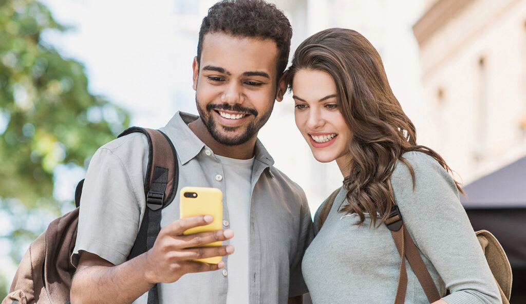 Male and female looking at a phone smiling